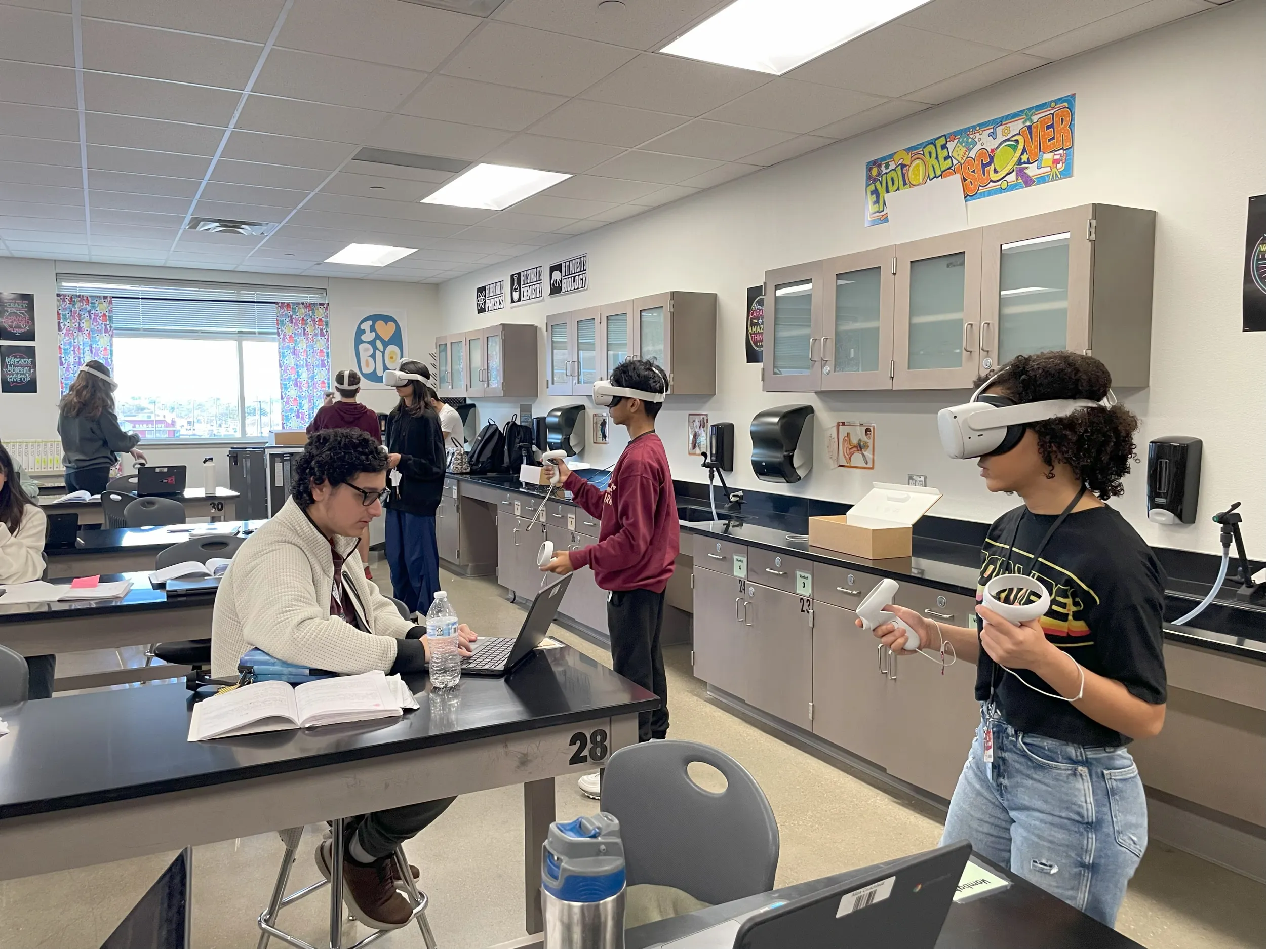 Students in a biology classroom, some in headsets, others at laptops